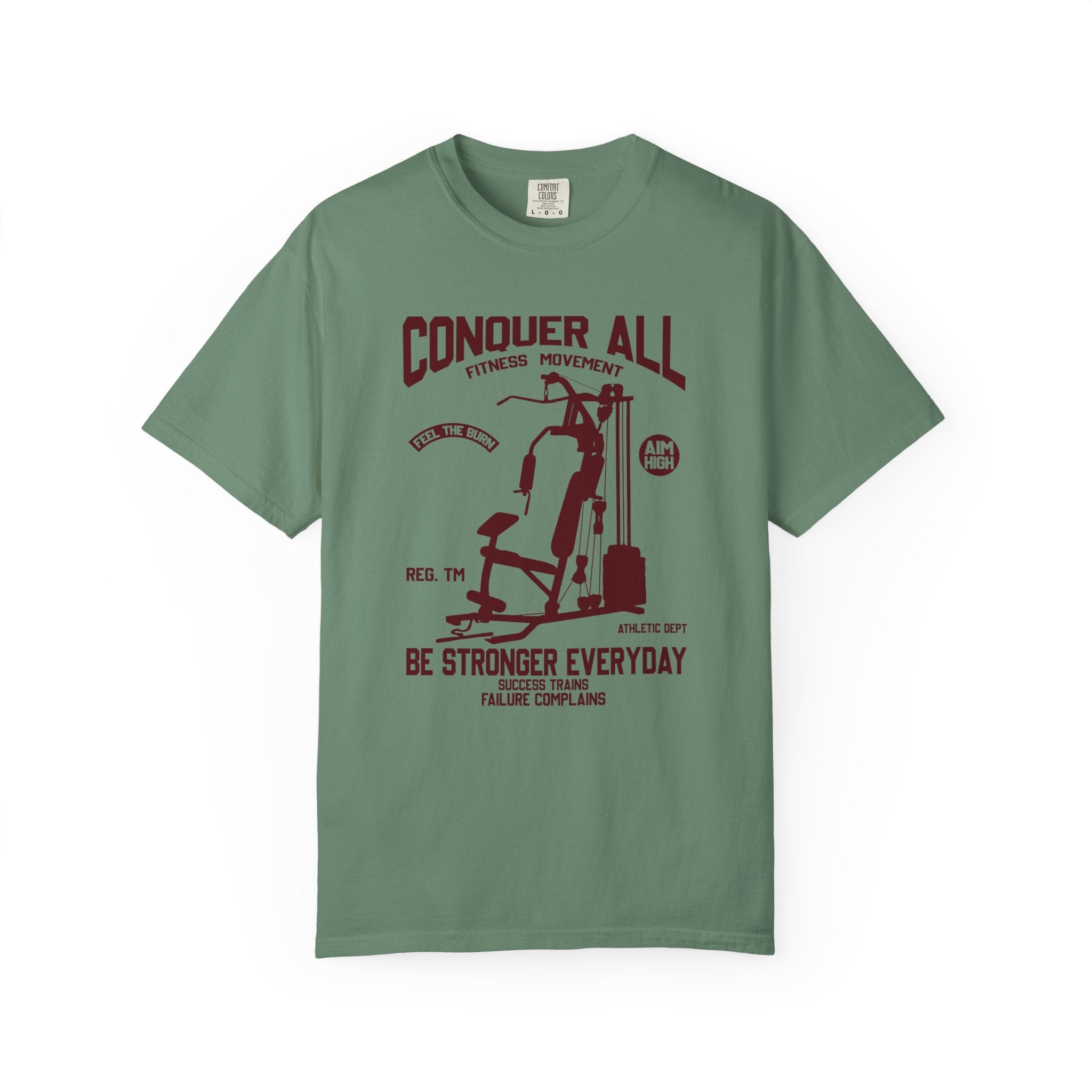 Green t-shirt with conquer all, be stronger everyday print on a white background